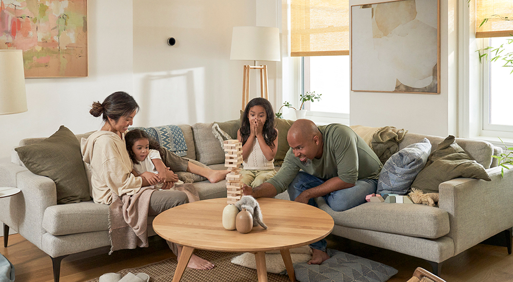 La foto de un hombre, una mujer y sus dos hijas jugando Jenga en la sala de estar.